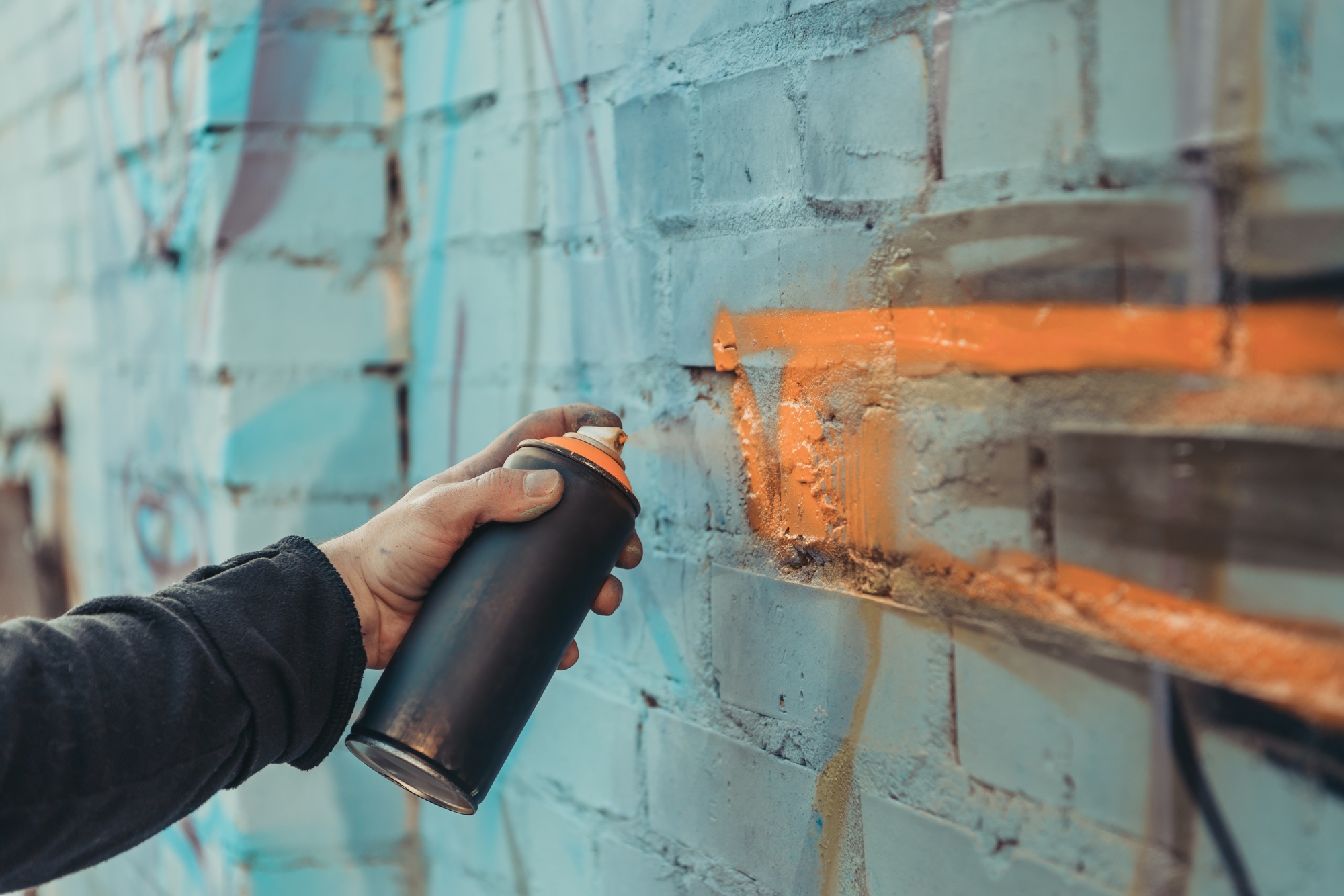 cropped view of street artist painting colorful graffiti on wall of building